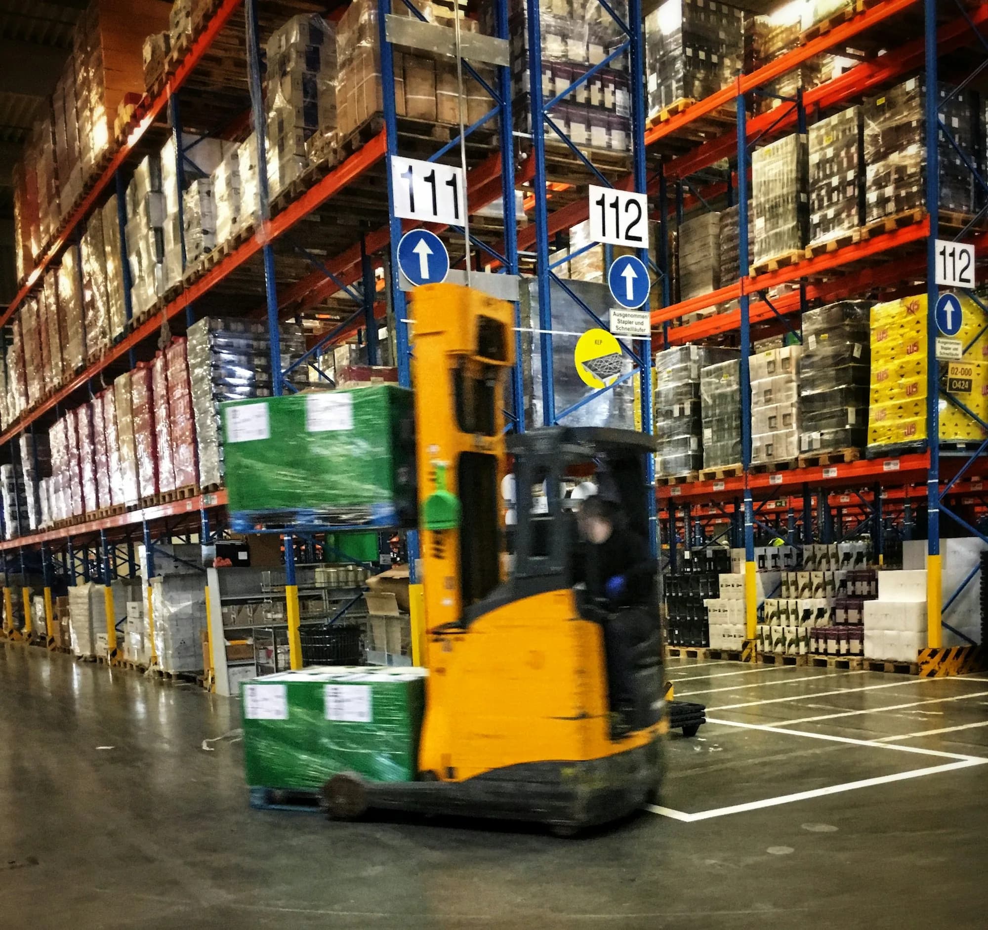Operação logística em centro de distribuição: empilhadeira entre porta-paletes