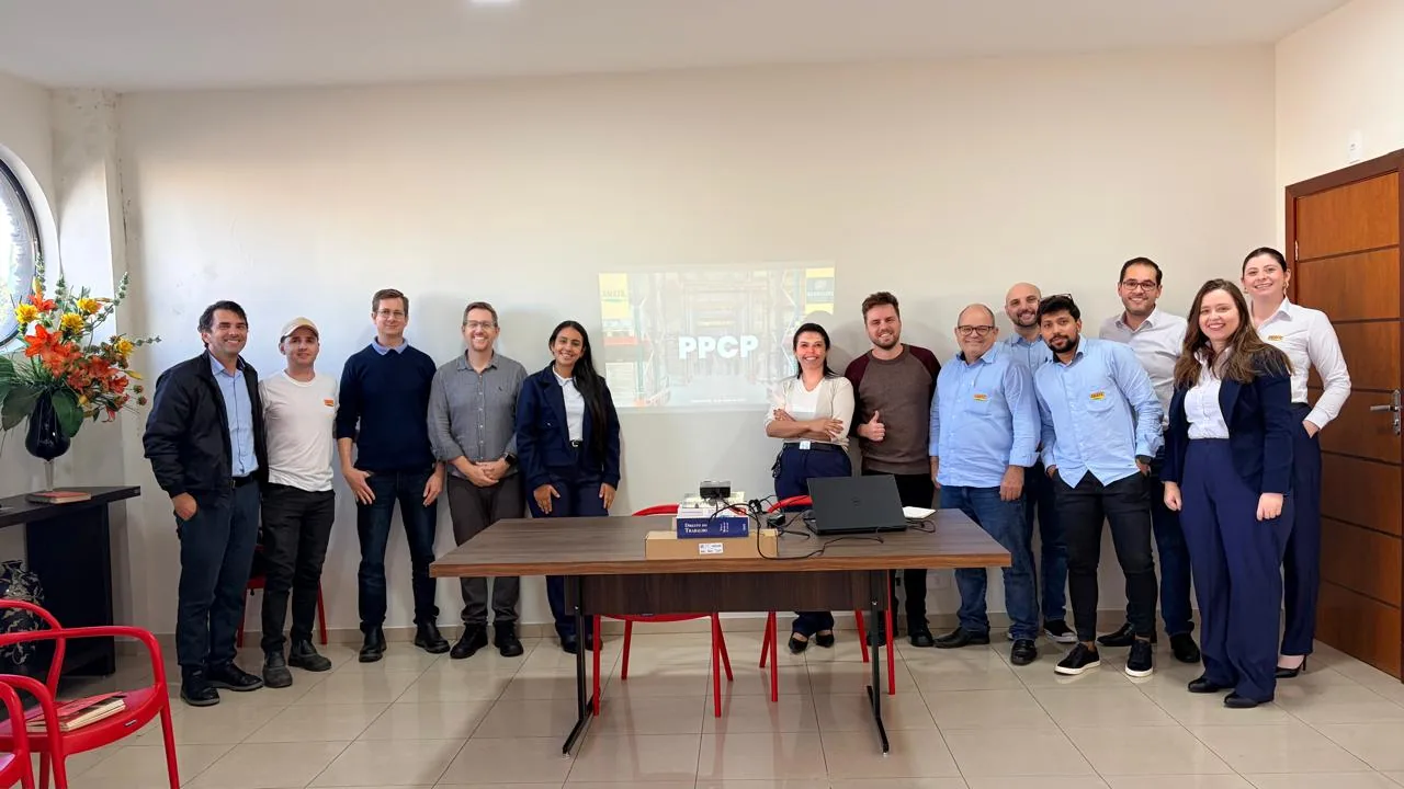 Reunião de plano de ação com a equipe do cliente e apresentação de PCP projetada.